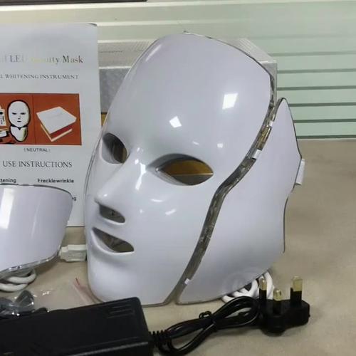 Woman using red light therapy mask at home